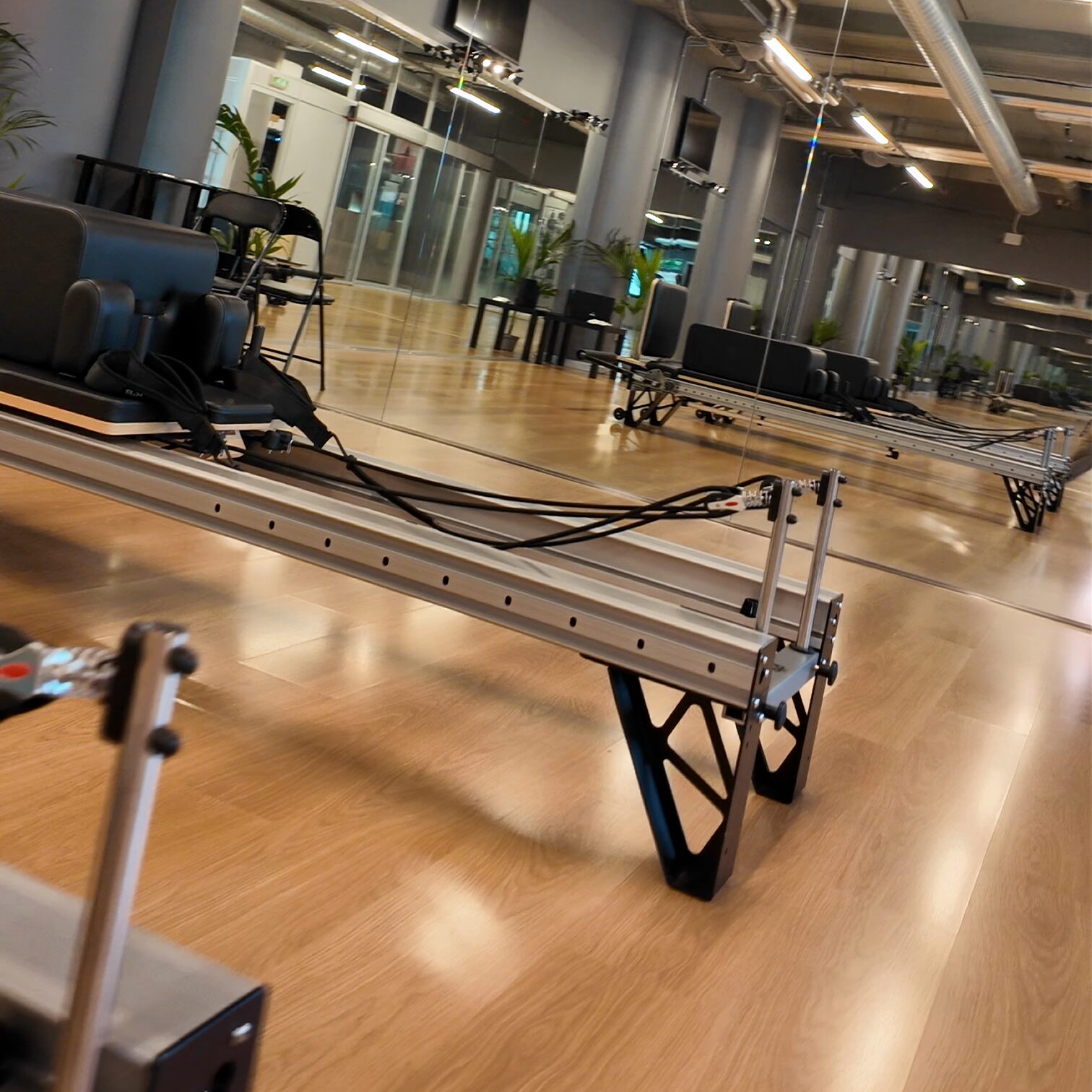 I Reformer in fila nella sala DELOS, pavimento in legno e pareti a specchio, luce diurna